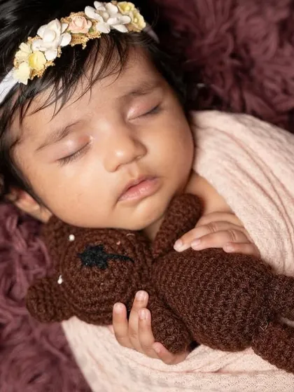 There is nothing more precious than a newborn's peaceful sleep. This close-up shot focuses on the delicate features and the comfort of a tiny teddy bear, creating a tender memory of those first few weeks.