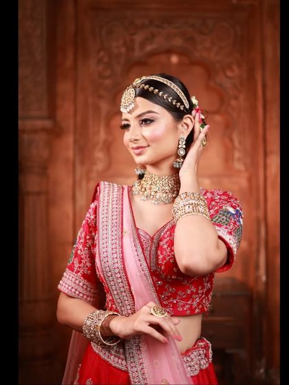 A radiant bride in a classic red and pink lehenga. The detailed embroidery on the blouse and the elegant matha patti complete this stunning wedding day look.
