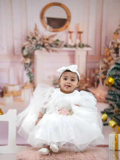 A winter wonderland for a first birthday. This little girl, dressed in a white angel-like dress, celebrates in our festive Christmas-themed studio.