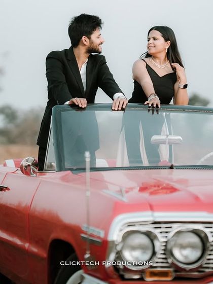 An intimate shot of a couple looking at each other over the windshield of a classic red convertible, capturing a moment of connection.