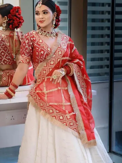 A unique combination of a white lehenga with a red Banarasi dupatta and blouse. This is perfect for brides who want a different look.