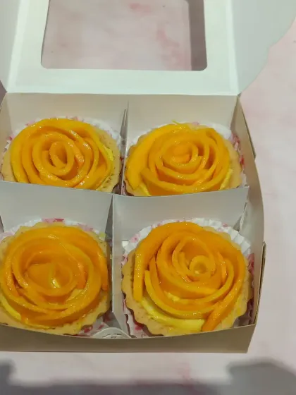 A box of four mini mango tarts, ready to go. They make a perfect gift or a wonderful treat for a small gathering, each one a little piece of edible art.