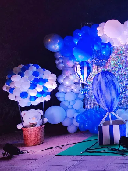 A close-up of a hot air balloon prop, featuring a teddy bear in a basket. This is a charming detail for a travel or sky-themed party.