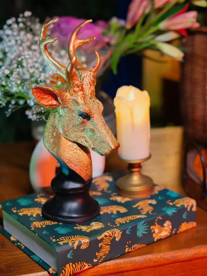 I blend rustic and glam elements, like this golden deer head sculpture placed on a book with a bold tiger print, illuminated by the soft flicker of a candle.