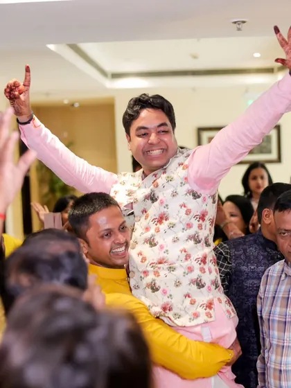The brother of the bride being lifted on someone's shoulders in celebration. A candid shot full of energy and happiness.