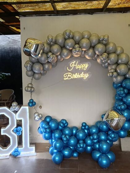 A cool blue and silver theme for a 31st birthday. This outdoor setup features a circular balloon arch, a neon sign, and large '31' marquee numbers.