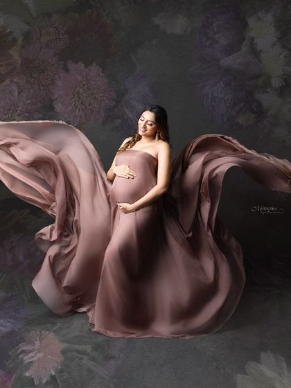 Capturing the glow and grace of motherhood, where each moment holds the promise of a new beginning. The flowing fabric and floral background create a work of art.