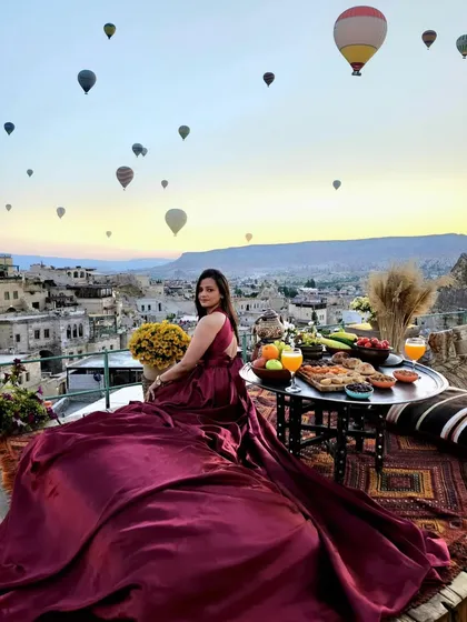A picture-perfect moment in Cappadocia. My client is seated for a scenic breakfast, her magenta trail gown cascading around her, with hot air balloons filling the sky.