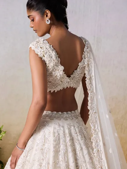 The beauty of this ivory lehenga lies in its details. This close-up reveals the intricate floral embroidery and delicate beadwork on the blouse, showcasing true artisanal craftsmanship.