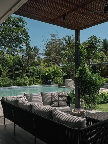The outdoor lounge area by the pool, perfect for relaxing in the shade. The comfortable outdoor sofa and the view of the tropical garden make it an ideal spot for unwinding.