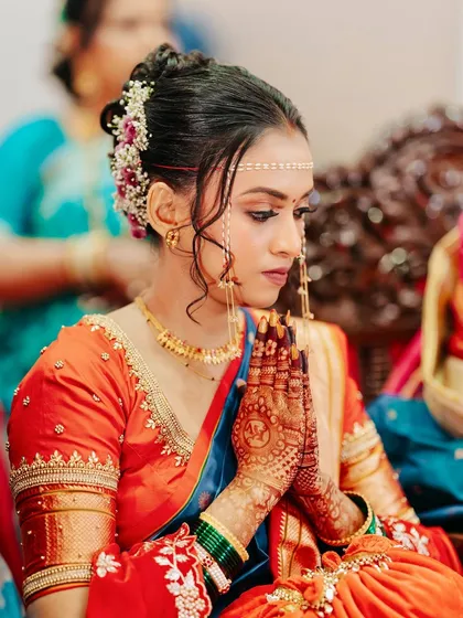 A moment of prayer and reflection. Her look is completed with a traditional mundavalya and a floral bun, showcasing the classic elements of a Maharashtrian wedding.