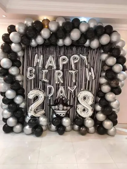 A bold black and silver balloon arch with a shimmer curtain, perfect for a 28th birthday celebration.