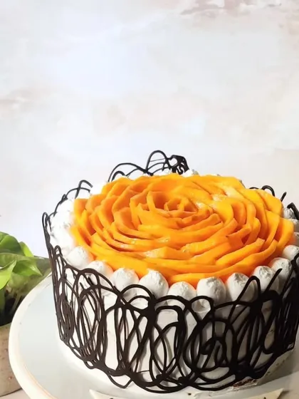 Celebrating the king of fruits, this Alphonso mango cake features a beautiful rose made from fresh mango slices. It's a flavor-forward choice that combines a light, eggless sponge with rich, creamy frosting and the sweetness of real mangoes, all surrounded by a delicate chocolate cage.