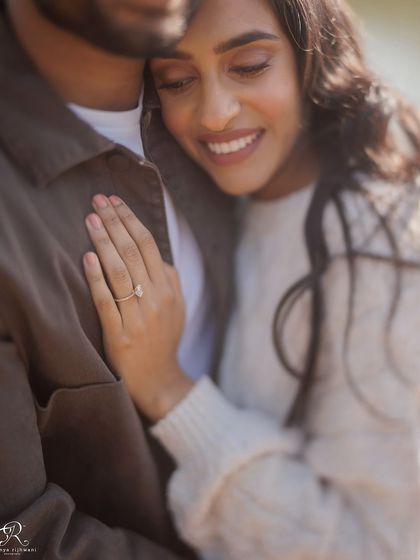 A close-up on her hand, showing off the engagement ring, as she holds him. This detail shot is a beautiful way to commemorate this special time in their lives.