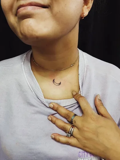 A small crescent moon tattoo placed subtly on the neck. It's an elegant and timeless piece for those who love celestial symbols.