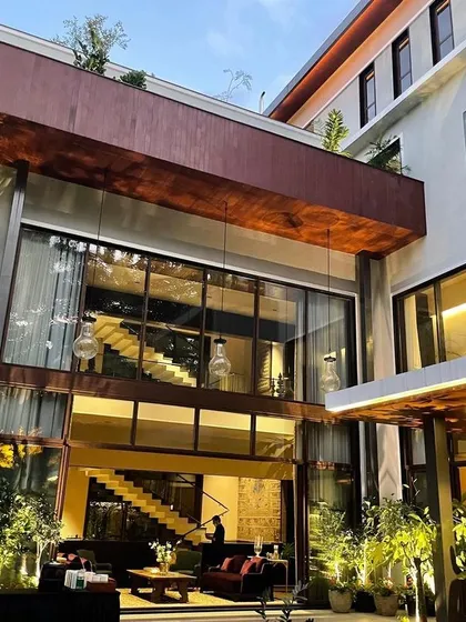 The double-height glass walls of this Koramangala residence blur the line between indoors and outdoors, a key element of our contemporary home design philosophy.