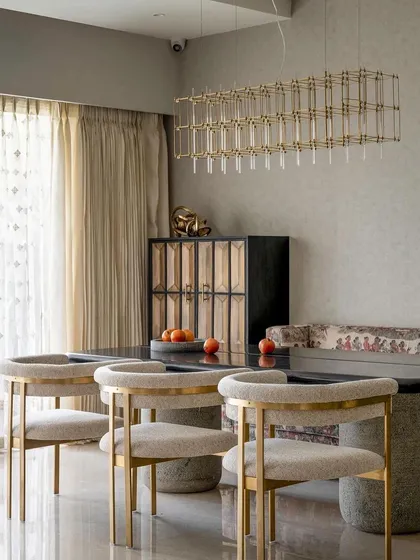 The dining room from the Studio Sylus project, showcasing our elegant dining chairs with upholstered seats and curved backs, set against a gold-finished metal frame.