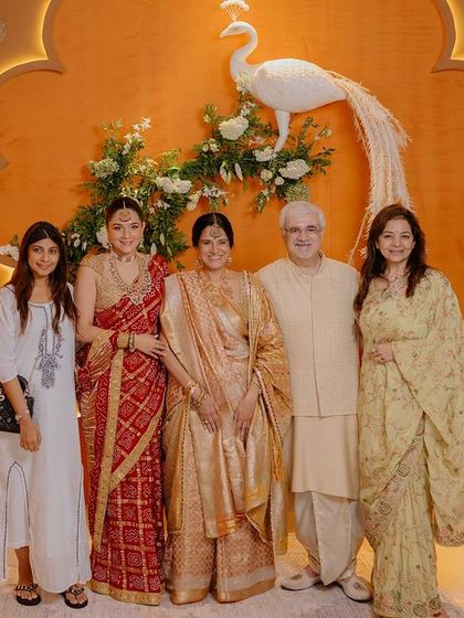 A beautiful family portrait taken at the Ambani-Merchant Graha Shanti Puja, in front of a custom backdrop featuring a white peacock and floral arrangements.
