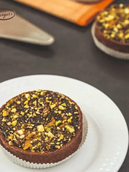 A close-up of our Chocolate Pistachio Tart. This dessert combines a rich chocolate base with the delightful crunch of chopped pistachios, offering a perfect balance of nutty and sweet flavours in a crumbly tart shell.