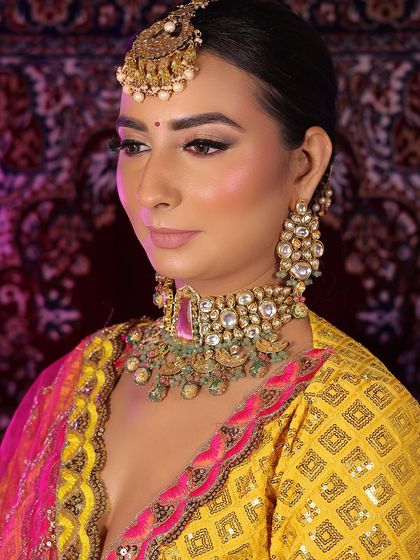 A regal look for a Teej festival celebration. The vibrant yellow lehenga is paired with bold makeup, including smokey eyes and a bright lip, complemented by traditional jewelry.
