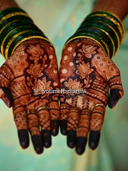 A beautiful, dark stain on a traditional lotus design. The contrast with the green bangles makes the rich color of the henna pop.