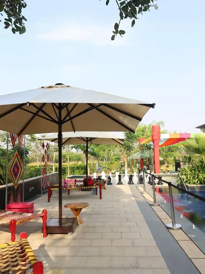 The poolside lounge area for the Holi party, decorated with traditional 'charpai' seating and colorful accents.