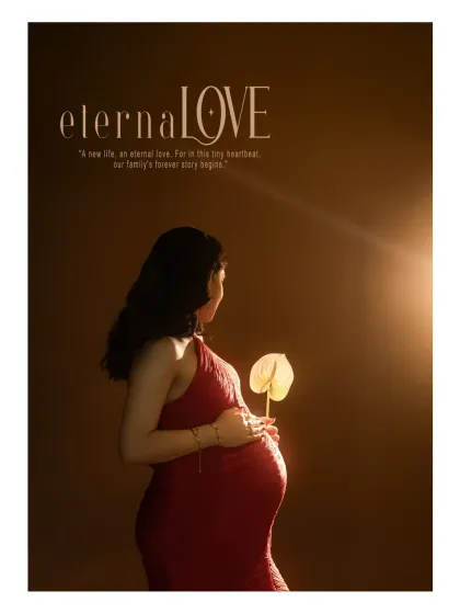 "eternaLOVE." This stylized studio portrait uses dramatic lighting to highlight the baby bump. The mother-to-be, in a striking red dress, holds a single flower, symbolizing the new life and eternal love that is beginning.