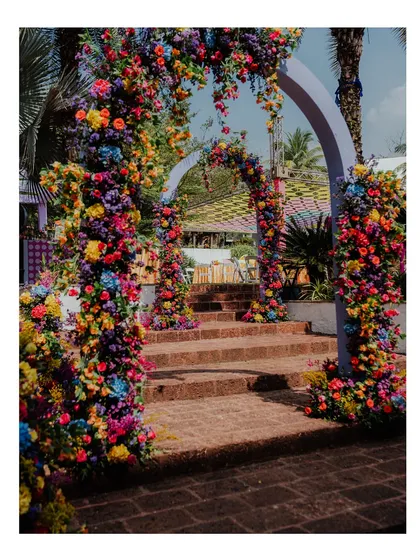 An entryway of cascading, multi-colored flowers creates a dramatic and welcoming entrance for a carnival-themed event at W Goa. It immediately signals to guests that they are in for a fun time.