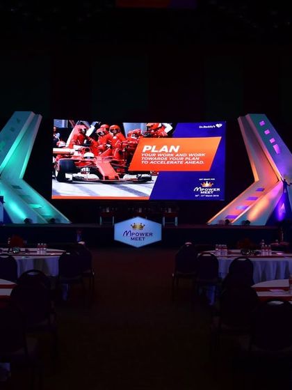 A futuristic and dynamic stage design for a corporate conference. The geometric structures and multiple LED screens create a high-tech and visually engaging backdrop for the event.
