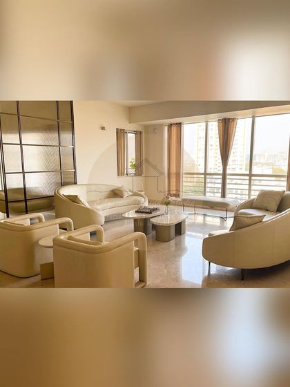 This ultra-luxurious living room uses curved sofas and armchairs to create a soft and inviting seating arrangement. The open layout and large windows fill the space with natural light.