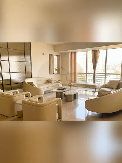 This ultra-luxurious living room uses curved sofas and armchairs to create a soft and inviting seating arrangement. The open layout and large windows fill the space with natural light.