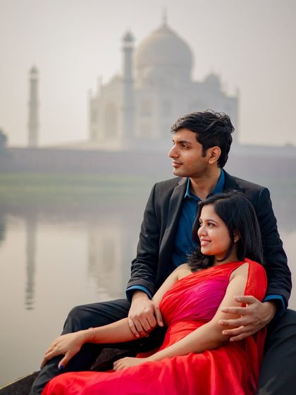 A peaceful moment on a boat, with the couple looking out towards the horizon, the Taj Mahal softly visible in the background.
