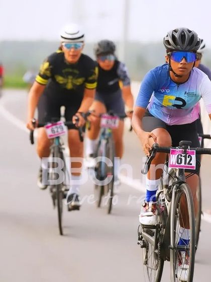 A female rider from the Racefit Coaching team, leading the pack.