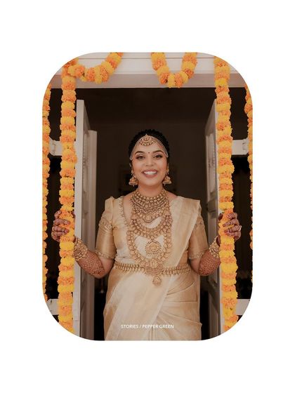 A joyful portrait of the bride framed by marigold garlands, her smile welcoming and bright.