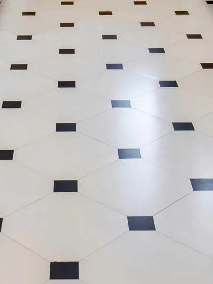 The classic black and white diamond pattern of the floor tiles adds a touch of graphic elegance and grounds the otherwise light and airy kitchen.