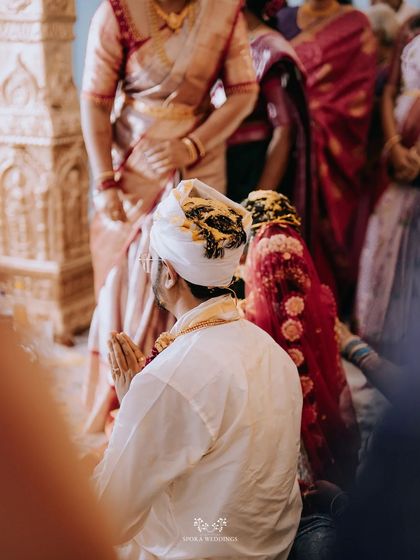 A view from behind the groom as he participates in the wedding rituals, surrounded by family.