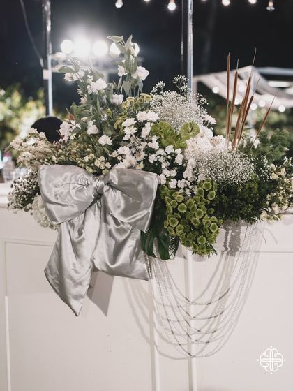 A beautiful floral arrangement with a large silver bow, part of the elegant decor for a seaside celebration.