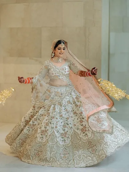 This bride is all smiles, twirling in her gorgeous white lehenga. The pearl jewellery adds a touch of soft, classic elegance.