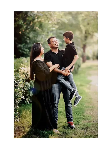 A family of three shares a laugh in a beautiful green parkway. We use natural light and surroundings to frame these happy, interactive family portraits.