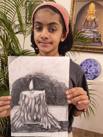 A student displays her impressive charcoal drawing of a melting candle, showing a great understanding of light, shadow, and texture.