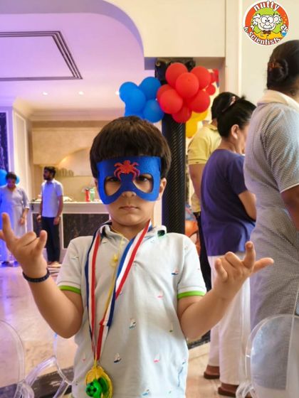 This little Spider-Man is showing off his web-slinging pose and the mask he made. He's also proudly wearing a medal he won during the superhero challenges.