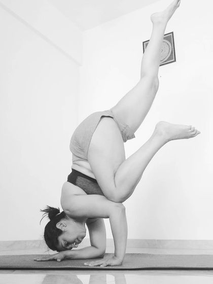 Extending one leg up in a Pincha variation. This challenges your stability and shoulder strength.