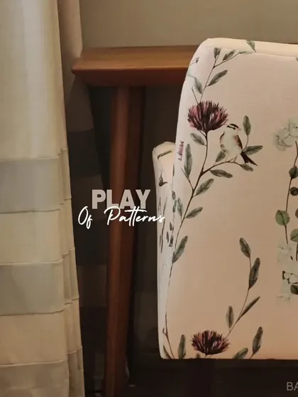 A beautiful play of patterns. Here, a floral-patterned armchair is placed next to striped curtains, showing how to mix different designs harmoniously.