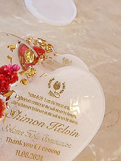 Work in progress on a heart-shaped Holy Communion favor, with preserved flowers and personalized text.
