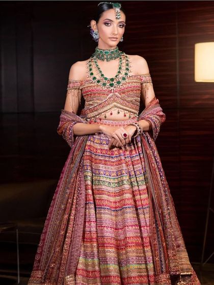 A full-length view of the modern bridal look, showing how the makeup complements the multi-coloured, striped lehenga.