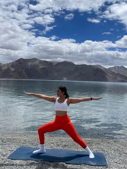Holding a strong Warrior II pose by Pangong Lake. This foundational yoga asana is incredible for building leg strength and focus, proving that true power comes from finding stillness and stability even in the most challenging conditions.