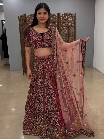 This maroon velvet lehenga offers a rich, royal look. The detailed floral embroidery makes it a true statement piece.