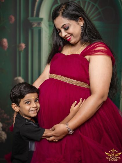 A big, happy smile from a future big brother. This studio maternity portrait is all about the joy and excitement a new baby brings to the family, captured with a simple and clean background to keep the focus on the emotion.