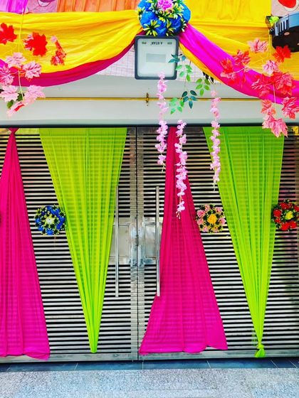 A simple yet eye-catching gate decoration with pink and lime green drapes, accented with hanging floral vines.