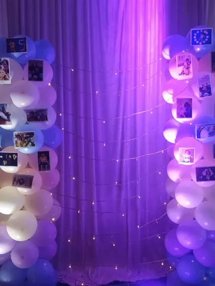 A creative way to display photos using two balloon pillars connected by fairy lights.